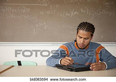 Picture - Peruvian student studying in classroom on laptop. Fotosearch
