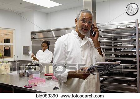 Stock Image - Small business owners working in bakery kitchen. Fotosearch