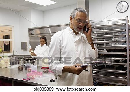 Stock Photo - Small business owners working in bakery kitchen. Fotosearch