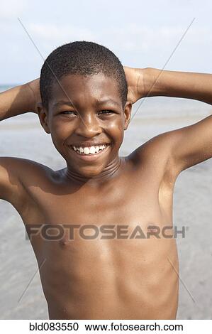Stock Image - Smiling African American boy on beach. Fotosearch