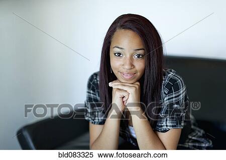 Stock Photography - Smiling mixed race girl with hands on chin. Fotosearch