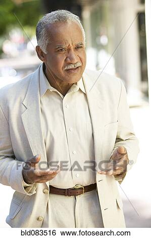 Uncertain Hispanic man standing outdoors View Large Photo Image Stock Photograph - Uncertain Hispanic man standing outdoors. Fotosearch