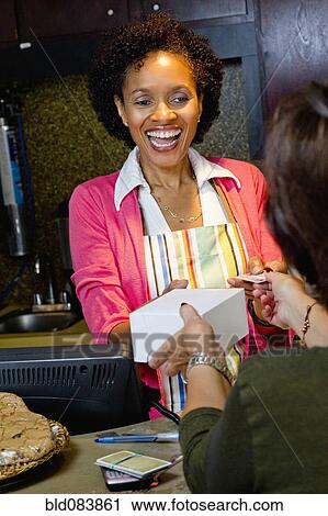 Stock Image - African American bakery owner taking customer's credit card. Fotosearch
