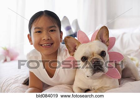 Asian girl laying on bed with costumed dog View Large Photo Image Stock Photo - Asian girl laying on bed with costumed dog. Fotosearch