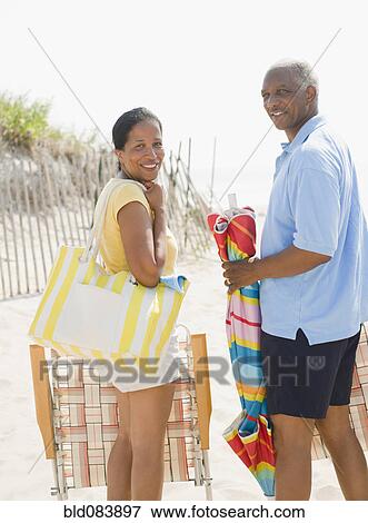 Black couple carrying beach gear together View Large Photo Image Stock Photo - Black couple carrying beach gear together. Fotosearch