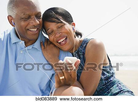 Stock Photo - Black couple on beach listening to music together. Fotosearch