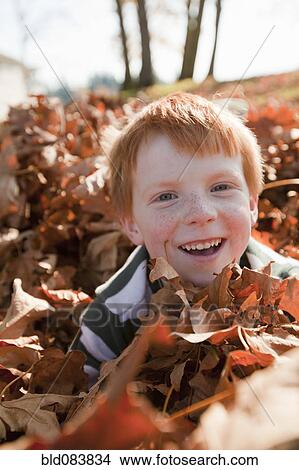 Picture - Caucasian boy playing in autumn leaves. Fotosearch