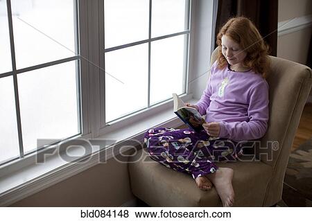 Caucasian girl reading on book near window View Large Photo Image Stock Photo - Caucasian girl reading on book near window. Fotosearch