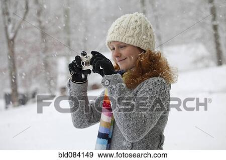Stock Photo - Caucasian girl taking photographs in snow. Fotosearch