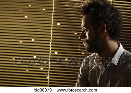 Caucasian man looking out window at night View Large Photo Image Stock Image - Caucasian man looking out window at night. Fotosearch