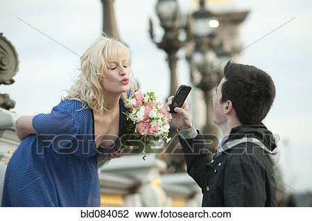Stock Image - Caucasian man photographing girlfriend. Fotosearch