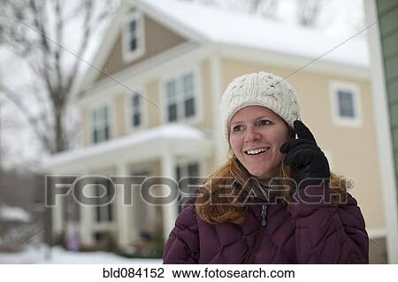 Stock Image - Caucasian woman using cell phone in snow. Fotosearch