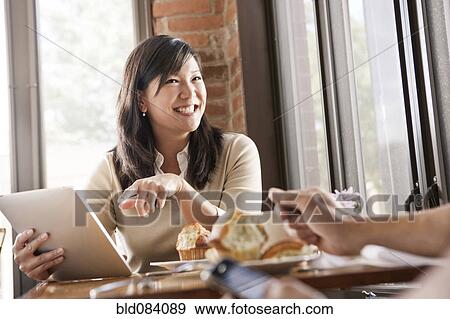 Stock Photo - Chinese woman using digital tablet in cafe. Fotosearch