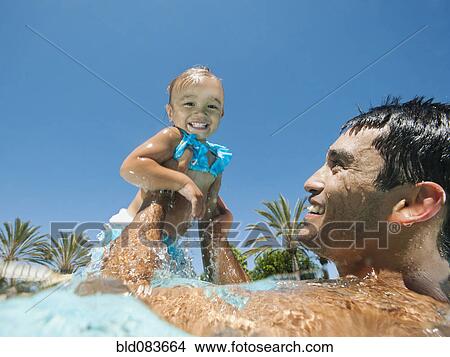 Picture - Father swimming in swimming pool with daughter. Fotosearch
