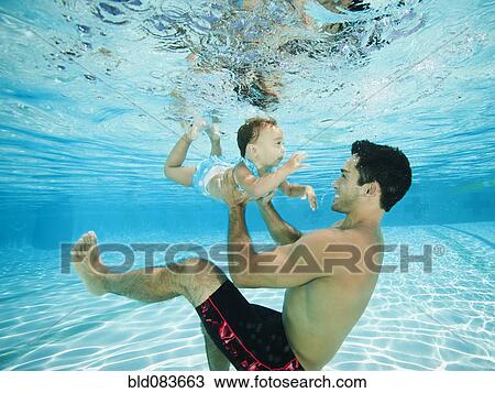 Father swimming underwater with daughter in swimming pool View Large Photo Image Stock Image - Father swimming underwater with daughter in swimming pool. Fotosearch
