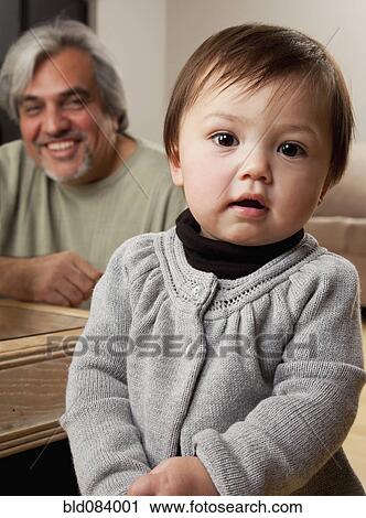 Stock Image - Grandfather and granddaughter in living room. Fotosearch