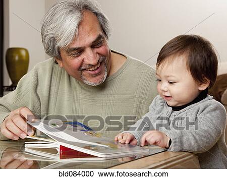 Stock Image - Grandfather reading book to granddaughter. Fotosearch