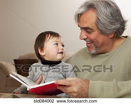 Stock Image - Grandfather reading book to granddaughter. Fotosearch