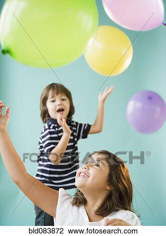 Stock Image - Hispanic brothers and sisters playing with balloons. Fotosearch