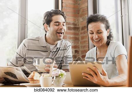 Stock Image - Hispanic couple using digital tablet in cafe. Fotosearch