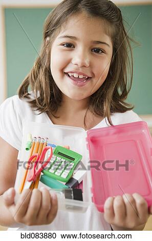 Stock Image - Hispanic girl holding school supplies. Fotosearch