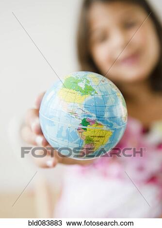 Stock Image - Hispanic girl holding small globe. Fotosearch
