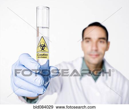 Stock Photo - Hispanic scientist holding test tube with caution sticker full of water. Fotosearch