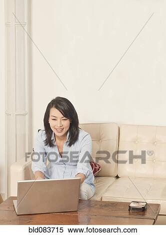 Korean woman using laptop in living room View Large Photo Image Stock Photography - Korean woman using laptop in living room. Fotosearch