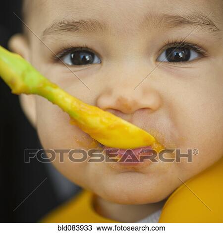 Stock Image - Mixed race baby eating from spoon. Fotosearch