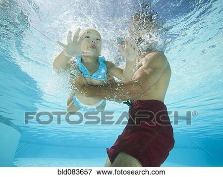 Mixed race father holding daughter in swimming pool View Large Photo Image Stock Photo - Mixed race father holding daughter in swimming pool. Fotosearch