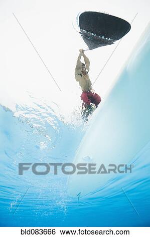 Stock Photograph - Mixed race man paddling on surfboard. Fotosearch