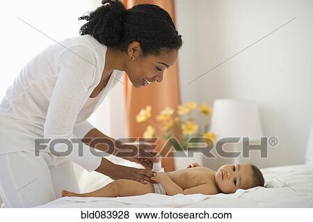 Stock Photo - Mixed race mother changing baby's diaper. Fotosearch