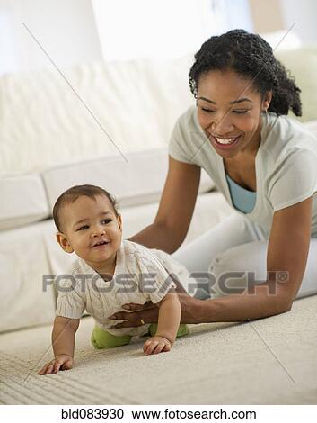 Stock Image - Mixed race mother playing with baby. Fotosearch