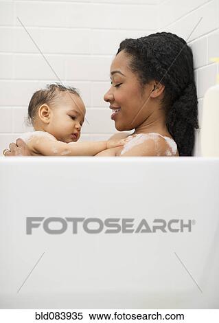Stock Photography - Mixed race woman bathing with baby. Fotosearch