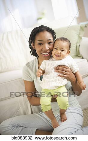 Stock Image - Mixed race woman holding baby. Fotosearch