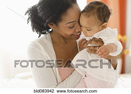 Stock Image - Mixed race woman holding baby. Fotosearch