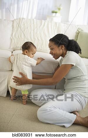 Stock Image - Mixed race woman playing with baby. Fotosearch