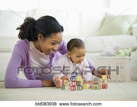 Stock Photo - Mixed race woman playing with blocks with baby. Fotosearch
