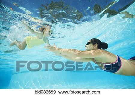 Stock Photo - Mother swimming in swimming pool with daughter. Fotosearch