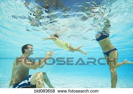 Stock Photo - Parents swimming in swimming pool with daughter. Fotosearch