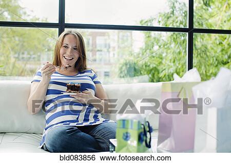 Pregnant Caucasian woman eating on sofa at baby shower View Large Photo Image Stock Photograph - Pregnant Caucasian woman eating on sofa at baby shower. Fotosearch