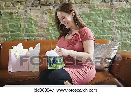 Pregnant Caucasian woman opening baby shower gifts View Large Photo Image Stock Photo - Pregnant Caucasian woman opening baby shower gifts. Fotosearch