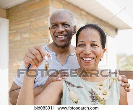 Stock Image - Proud Black couple holding keys to new home. Fotosearch