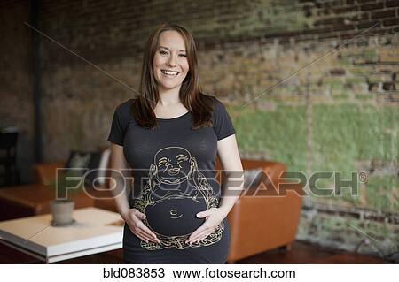 Stock Image - Smiling pregnant Caucasian woman holding stomach. Fotosearch