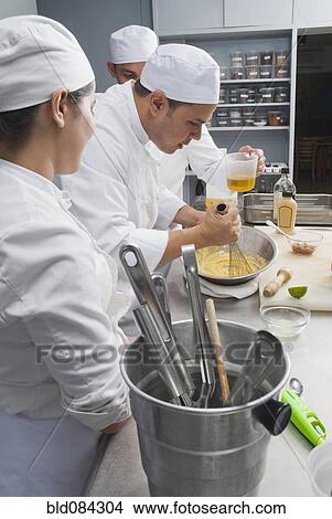 Picture - Baker stirring batter in bakery kitchen. Fotosearch