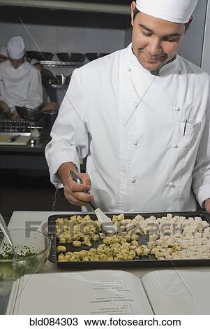 Stock Image - Baker working in bakery kitchen. Fotosearch
