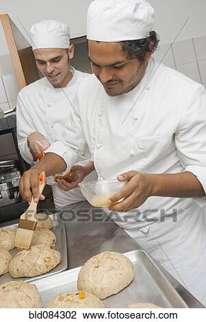 Stock Image - Bakers preparing bread in bakery kitchen. Fotosearch