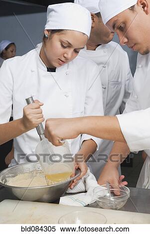Stock Photography - Bakers stirring batter in bakery kitchen. Fotosearch