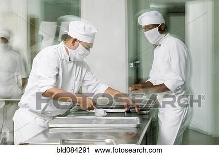 Stock Image - Baker's working in bakery kitchen. Fotosearch