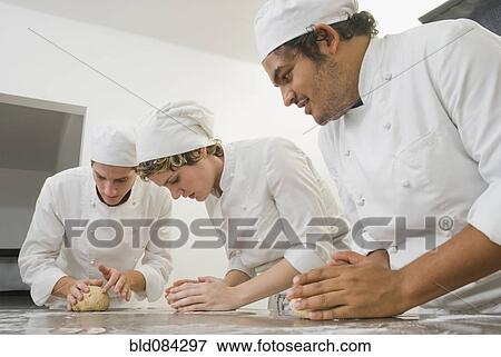 Stock Photo - Bakers working with dough in bakery kitchen. Fotosearch